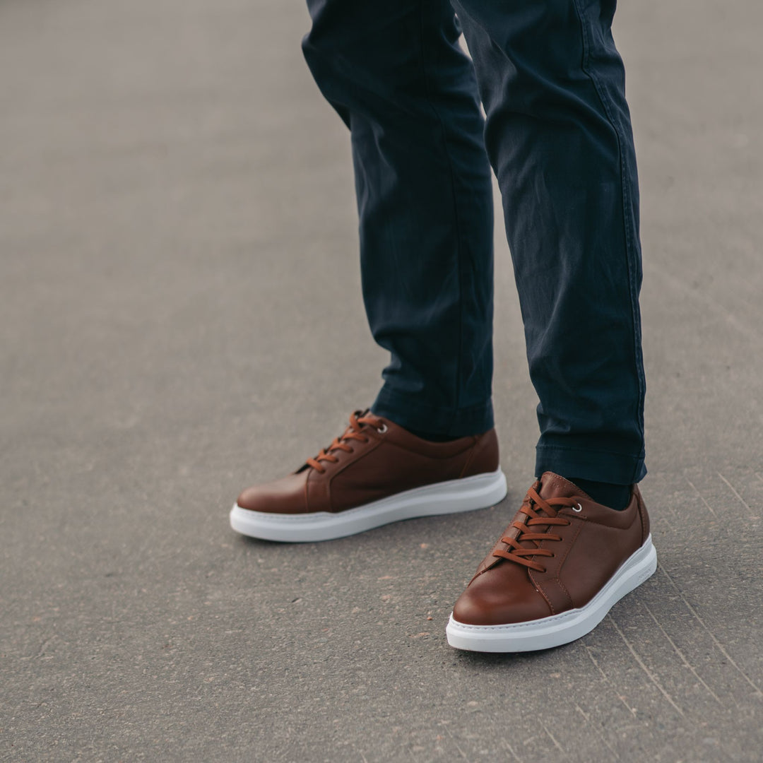 Person standing on asphalt wearing the SAVI sneaker.