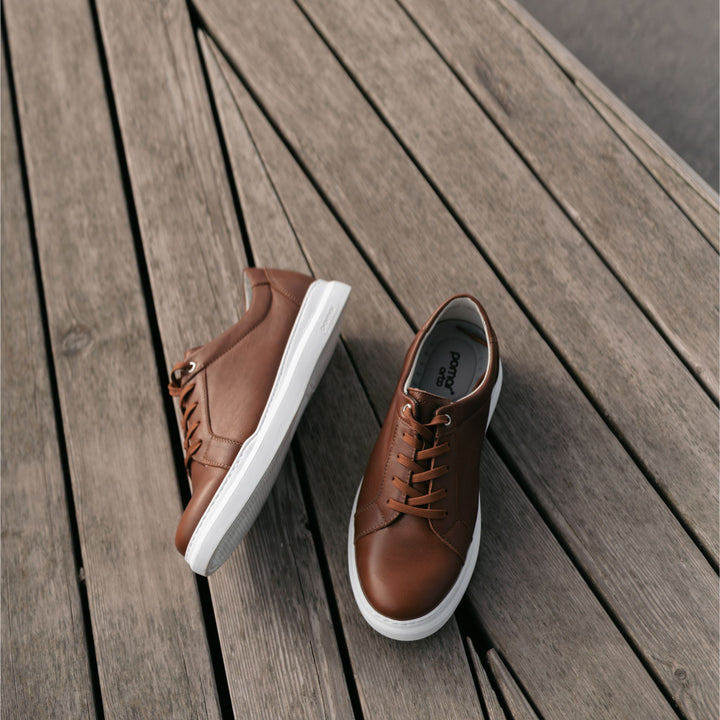 Brown men's sneakers on a bench outdoors.